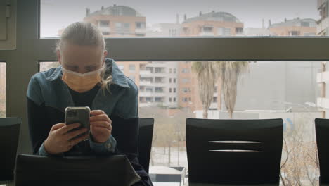 mujer con máscara usando teléfono inteligente en la sala de espera