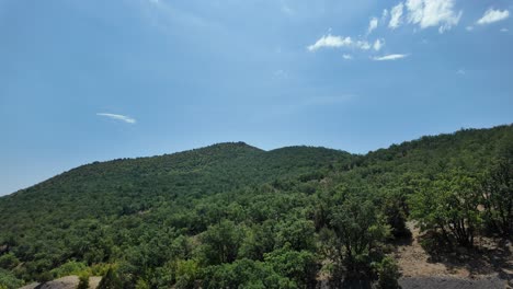 a sunny day with blue skies and white clouds over a green, forested mountain range in crimea