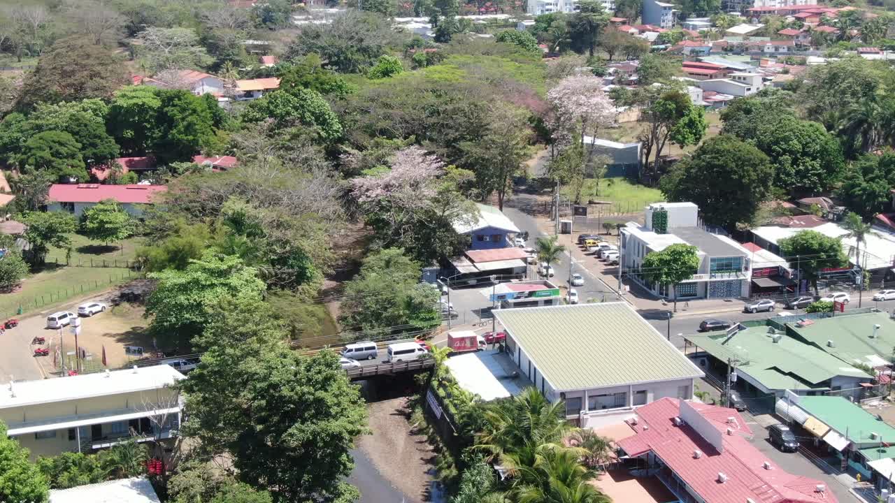 drone de la playa de costa rica volando sobre jaco, una típica ciudad centroamericana con pequeñas casas, un río y rodeado de un bosque con la montaña verde en el horizonte en un día soleado