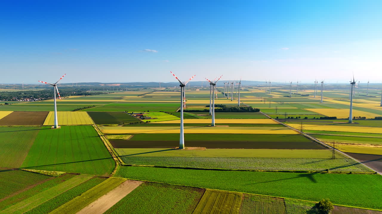 Colorful patched field with wind farms. Vast plantations with numerous wind mills working on. Aerial view