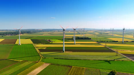 colorful patched field with wind farms. vast plantations with numerous wind mills working on. aerial view