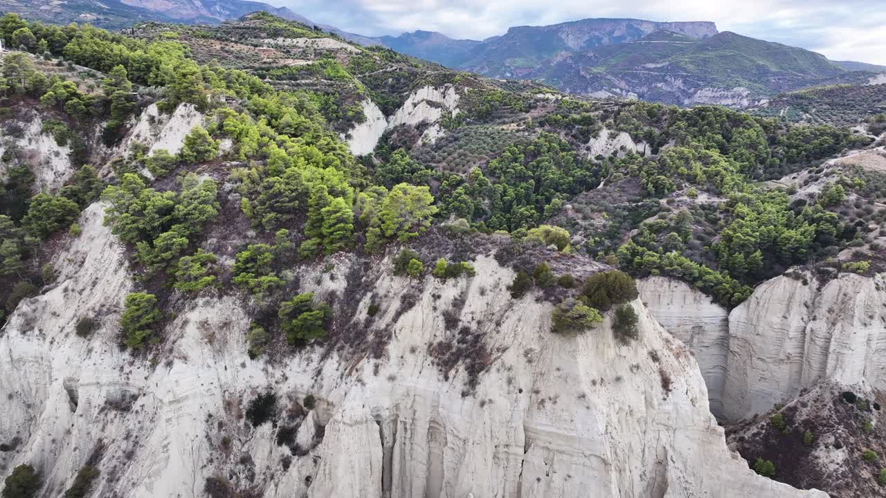 dramatic steep stark white cliffs with vibrant greenery off the coast of Corinth in Greece during sunset TRUCKING LEFT PAN RIGHT TILT DOWN