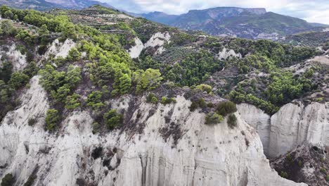 dramatic steep stark white cliffs with vibrant greenery off the coast of corinth in greece during sunset trucking left pan right tilt down