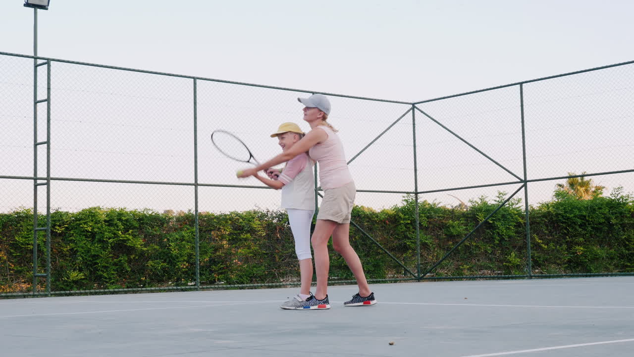 La mamma sta cercando di insegnare a giocare a tennis: attività familiari