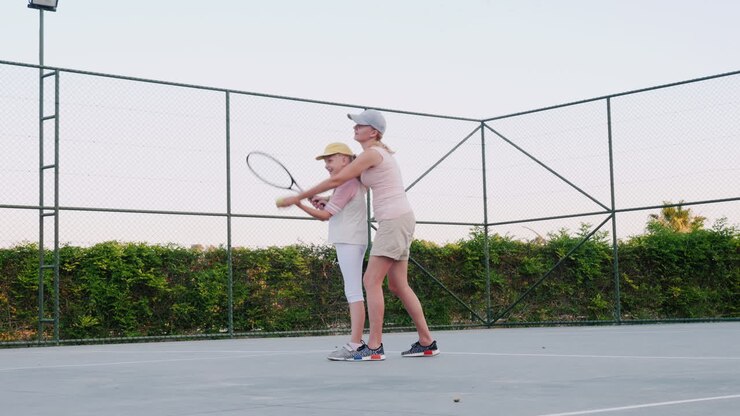 La mamma sta cercando di insegnare a giocare a tennis: attività familiari