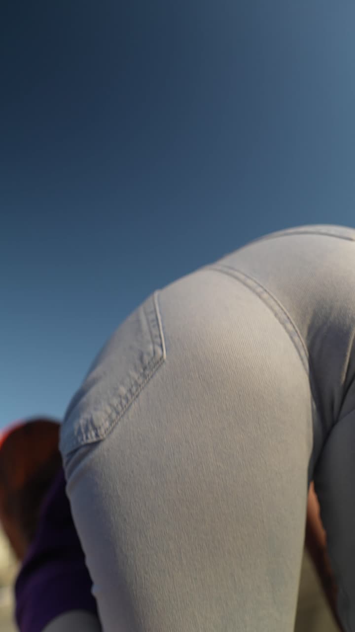 Woman in purple shirt and blue jeans looking up at the sky