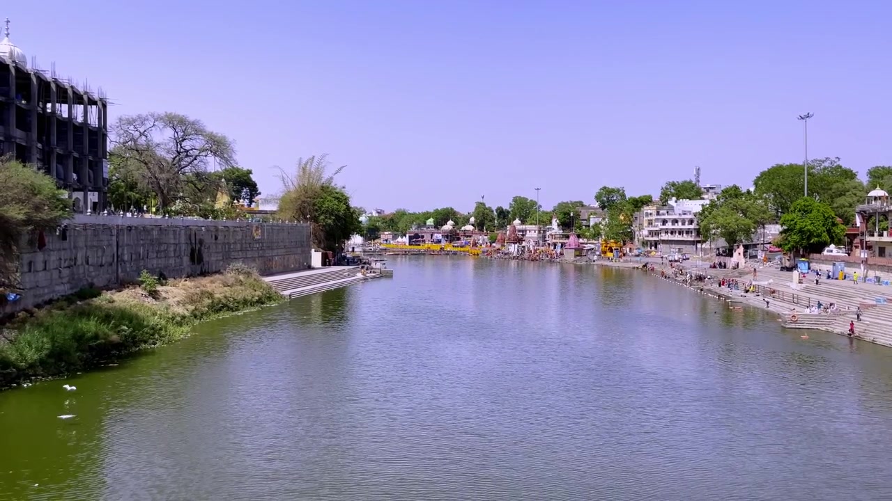Ripresa a mano dal Ponte Narasingh Ghat con vista su Shri Ram Ghat e il sacro fiume Kshipra a Ujjain. Ghat dei templi, architettura fluviale e dintorni di pellegrinaggio visibili durante il giorno.