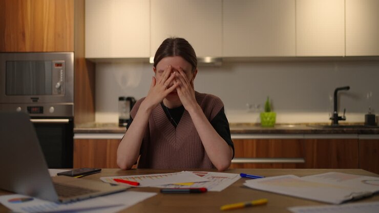 A pensive woman looks at the documents and the graphs on the table make notes in the papers. A tired woman works from home. Distance Learning Analysis and Planning