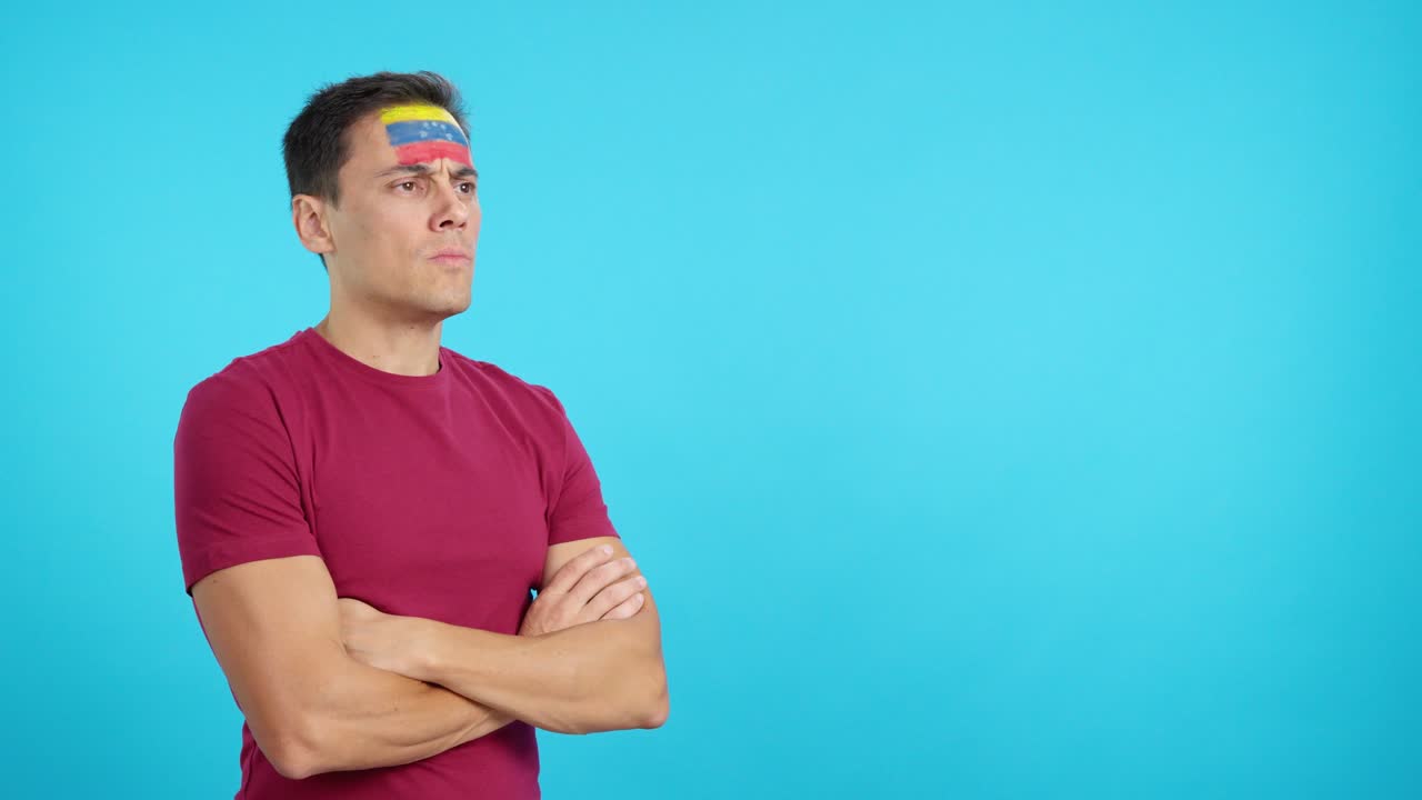 Man with venezuelan flag painted looking away with serious expression