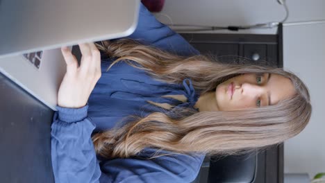 focused woman working on laptop in domestic environment, vertical view