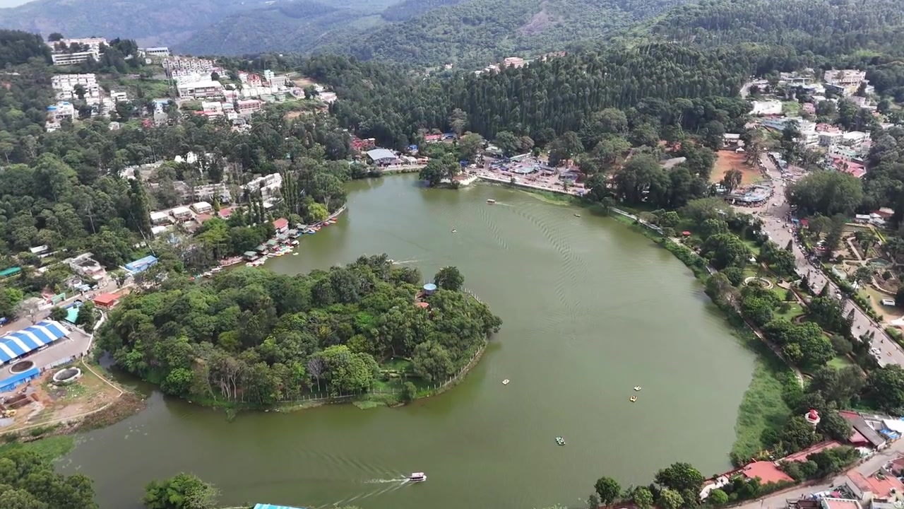 A mesmerizing droneshot over Yercaud Lake reveals emerald waters a picturesque island, vibrant hill-town life,highlights peaceful boating and endless green valleys framed by the majestic Eastern Ghats