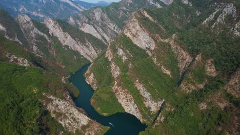 mountain lake in the albanian alps with rocky slopes, high peaks, touring boats sailing through the valley