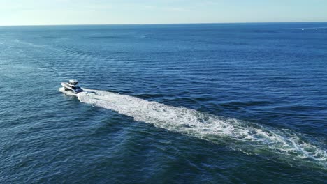 a yacht moving in middle of the sea in caribbean aerial view video background in 4k | beautiful yacht with trail in water moving drone shot video background