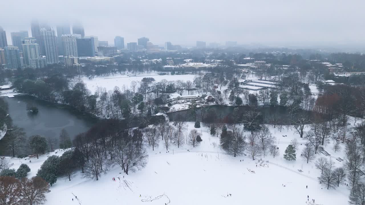 Aerial push in on snow covered Lake Clara Meer and Piedmont Park in Atlanta.