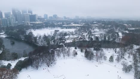aerial push in on snow covered lake clara meer and piedmont park in atlanta.