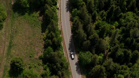 Coche-Conduciendo-Por-Una-Sinuosa-Carretera-Asfaltada-A-Través-De-Bosques-Verdes-En-Las-Montañas,-Siguiendo-Tomas-Aéreas