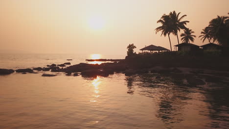 impresionante puesta de sol palmeras en la playa costa de goa india en la india trópico goa en la bahía del mar arábigo océano índico puesta de sol de la playa cinematográfica aérea pan izquierda movimiento