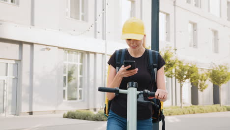 woman delivery person using smartphone on electric scooter