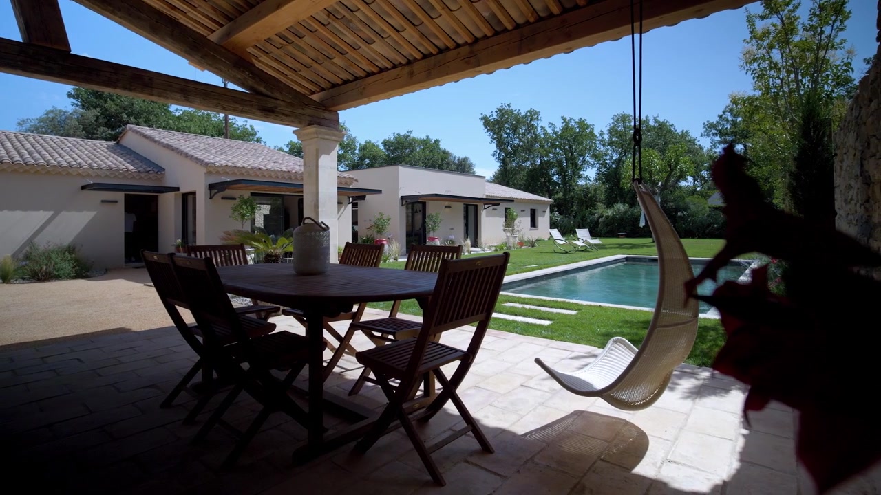 Ripresa che rivela lentamente una sedia e un tavolo sospesi in un giardino di villa.