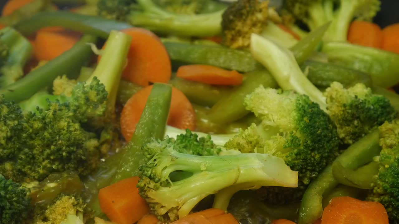 green bell pepper, broccoli, and carrots cooking in a pan close up
