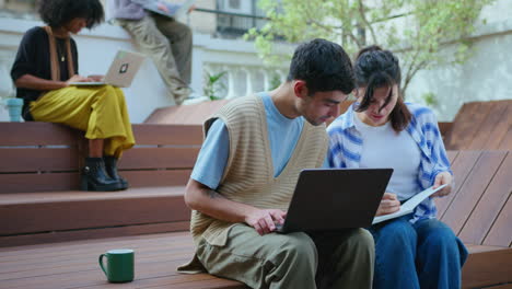 young businessman and businesswoman working with laptop outdoors in the city