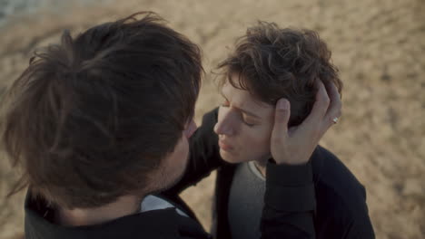 affectionate man kissing forehead of beloved girlfriend outdoors
