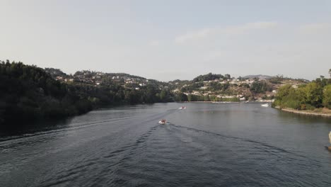 fly over rio douro, motorboats cruising the calm flow of water, castelo de paiva, portugal