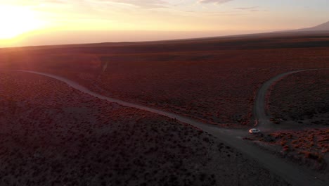 aerial cinematic shot of two travelers on a dirt road at sunset in the atacama desert, chile, south america