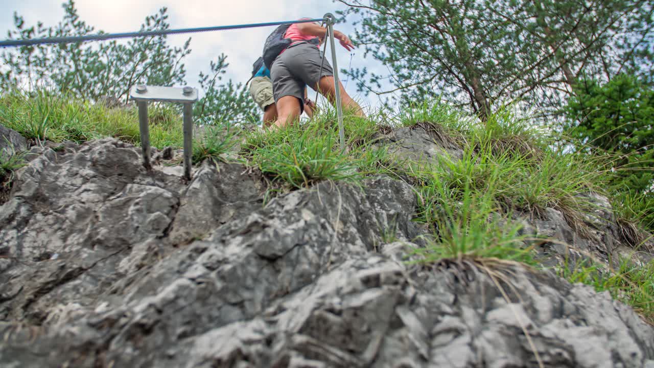 Active Man And Woman Climb Down Steep Rock Face