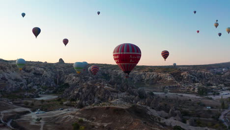 una flotilla de globos aerostáticos volando sobre los paisajes jurásicos de goreme cappadoica, turquía