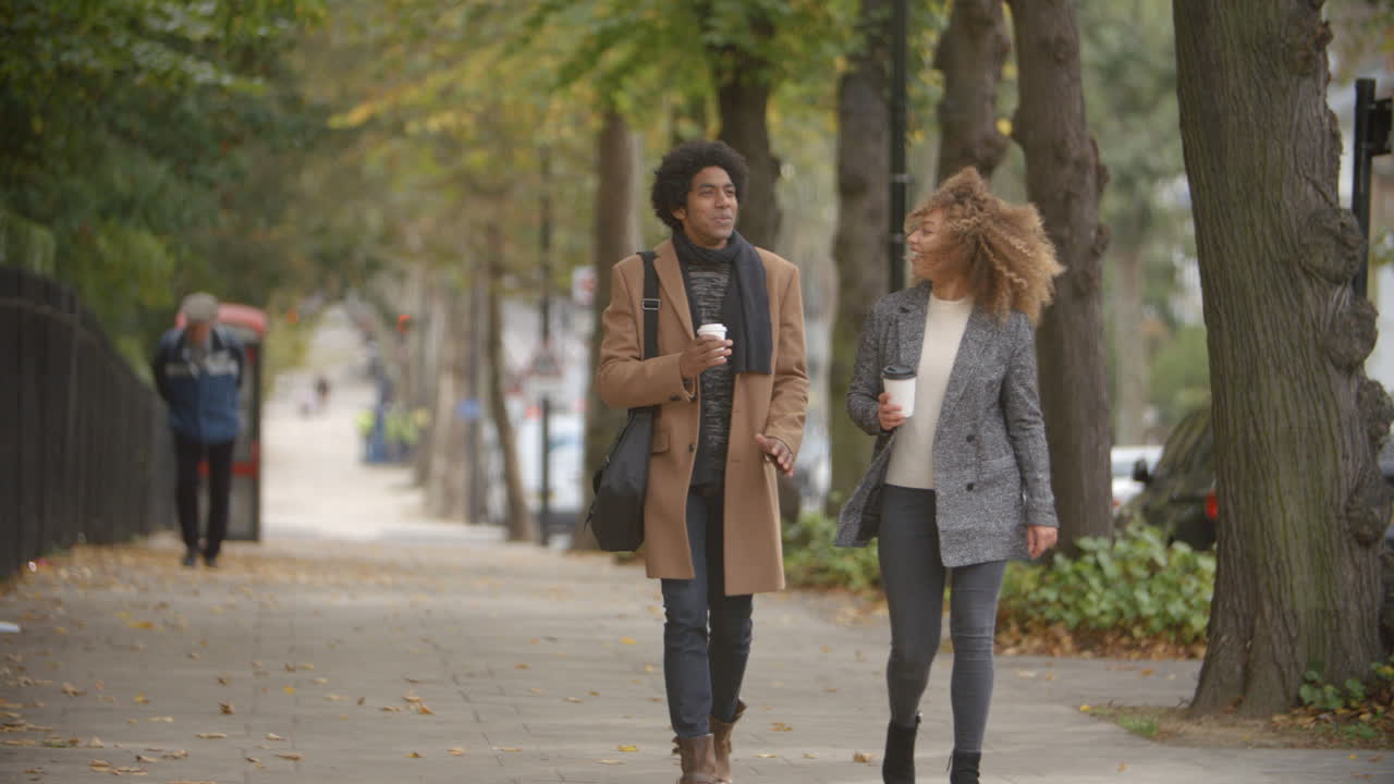 Pareja elegante paseando por una calle otoñal en la ciudad en cámara lenta