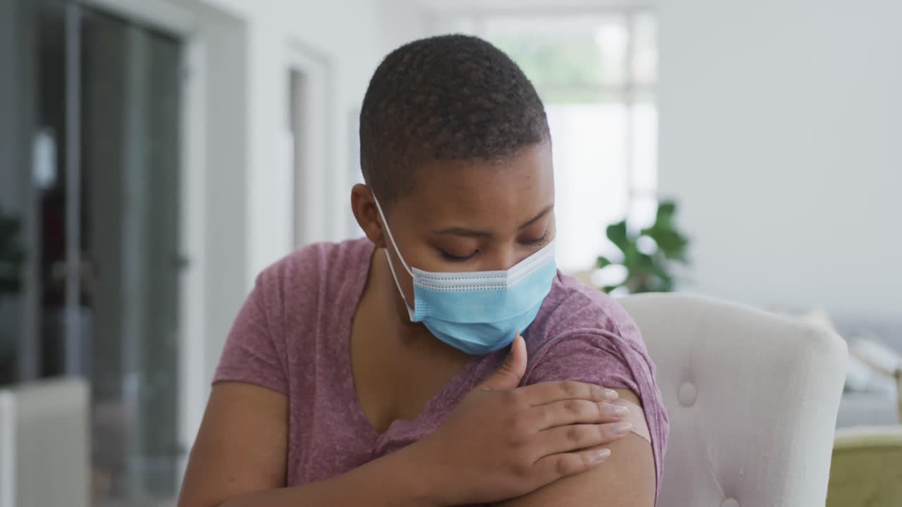Ritratto di una felice donna afroamericana taglia forte con mascherina e cerotto sul braccio dopo la vaccinazione.