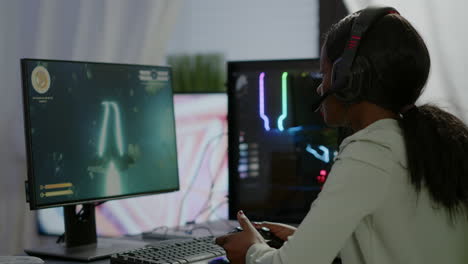 jugador africano profesional jugando un juego de disparos espaciales en línea en una computadora poderosa