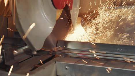 work in production with metal. a disk that rotates and cuts metal close up. sparks flying from the place of cutting metal.