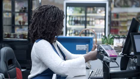 smiling african american cashier scanning goods at checkout