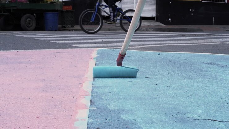 Witness the transformation of a street as vibrant shades of blue come alive under the skilled strokes of a painter, turning the ordinary into a work of art