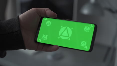 Mockup. Smartphone with horizontal green screen chroma. Telecommuting, having a videocall, watching online movie. Close-up.