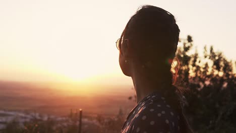 slow motion shot of a beautiful model looking over the valley with a vibrant sunset