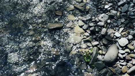 clean creek on pebbles background with huge mountain boulder. fast water flow.