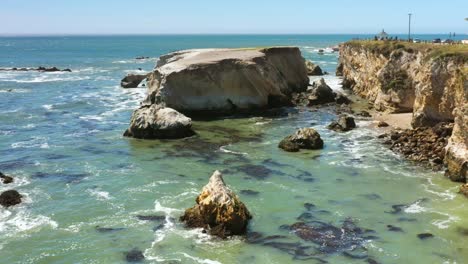 a picturesque rocky shoreline near pismo beach with gentle waves - aerial view in slow motion