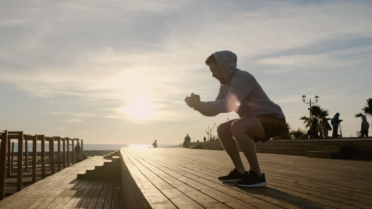 나무로 만든 해변 산책로에서 해가 지는 동안 스을 하는 남자
