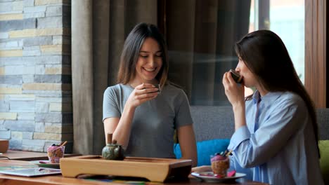 two pretty girlfriends talk and drink tea in cafe