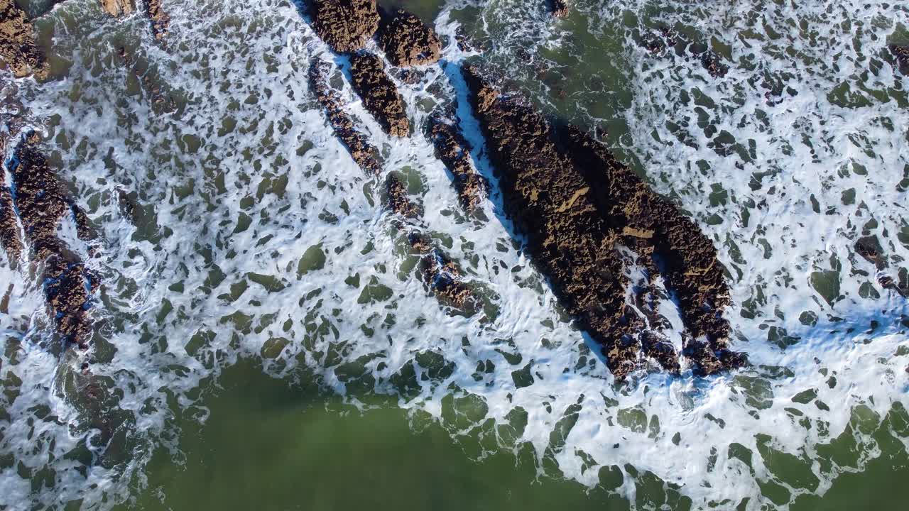 Aerial Top Down Static View of Large Sea Waves Breaking and Hitting Rocks