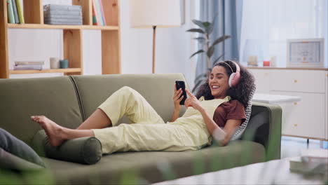 young woman relaxing on couch with headphones and phone