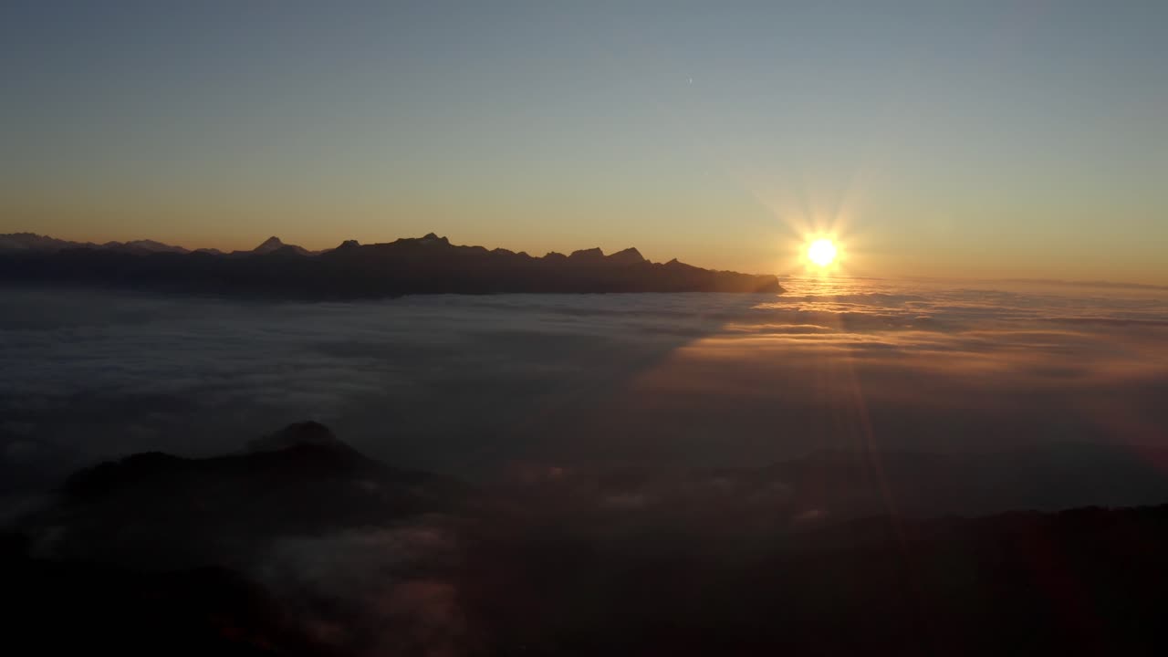 alto vuelo por encima de la niebla al atardecer, los alpes en el fondo - suiza