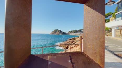 vista a través de un marco de metal que pasa por la bahía de tossa de mar en el fondo