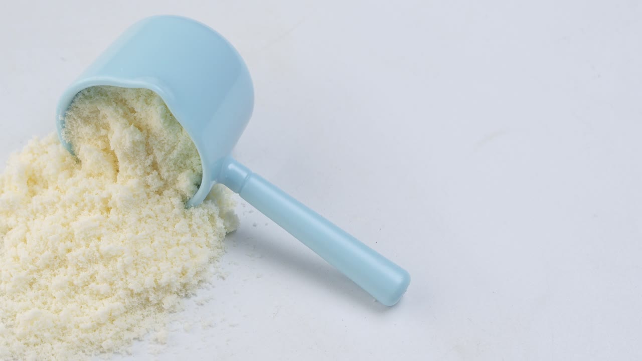 Close up of baby milk powder and spoon on tile background