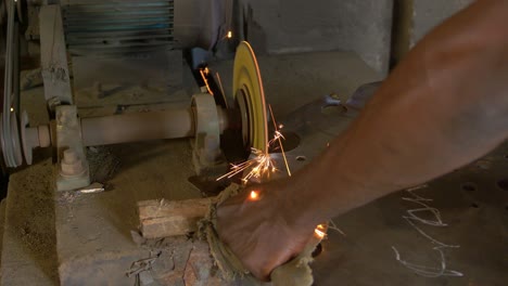 manos de un trabajador africano pulindo una sierra obteniendo chispas de cerca de su artesanía
