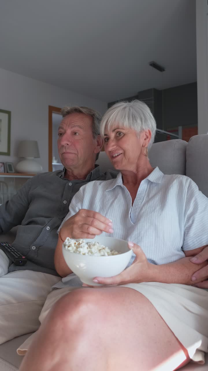 Casal de idosos assistindo à TV com pipoca