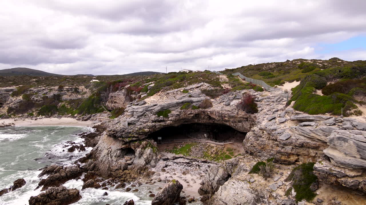 Aerial pullback from historic Klipgat Cave cavern set in limestone coastal cliff